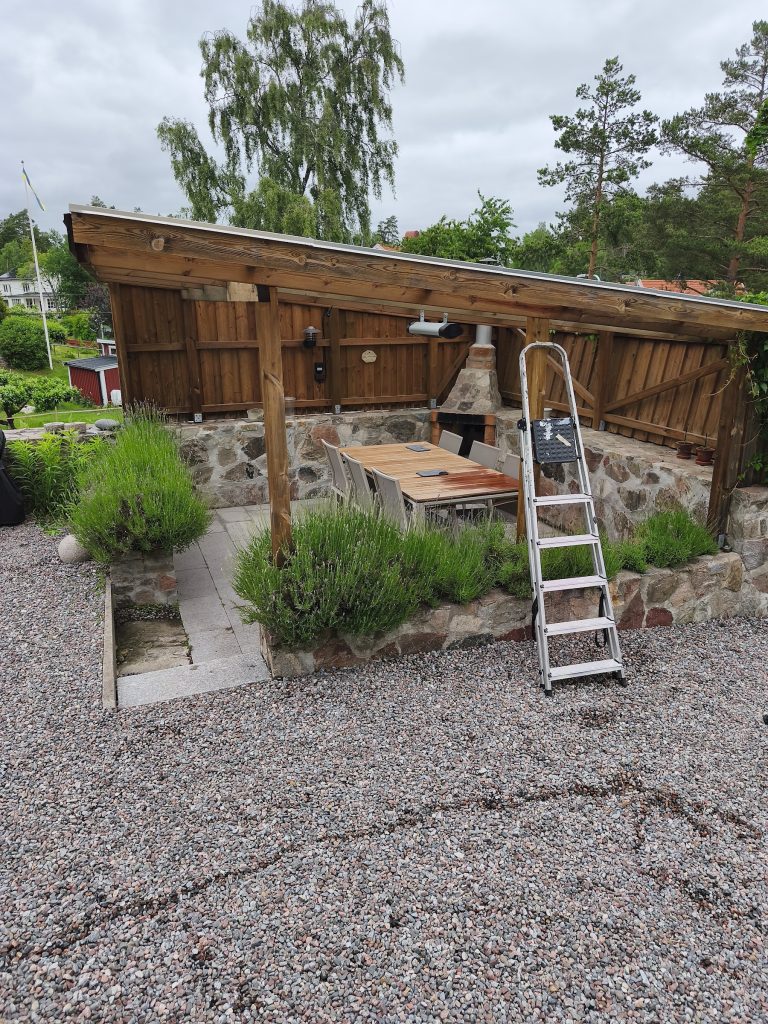 Puidust grillmaja, kivimüür ja aiamööbel õuealal