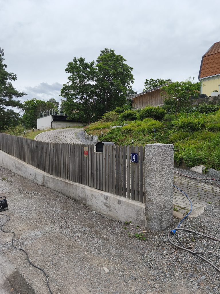 Ilmastikust hallinud puitaed ja kivimüür sissesõidutee ääres
