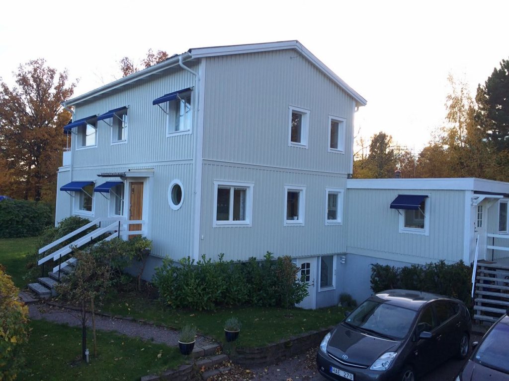 Helesiniseks värvitud kortermaja, valged piirded ja sinised varikatused