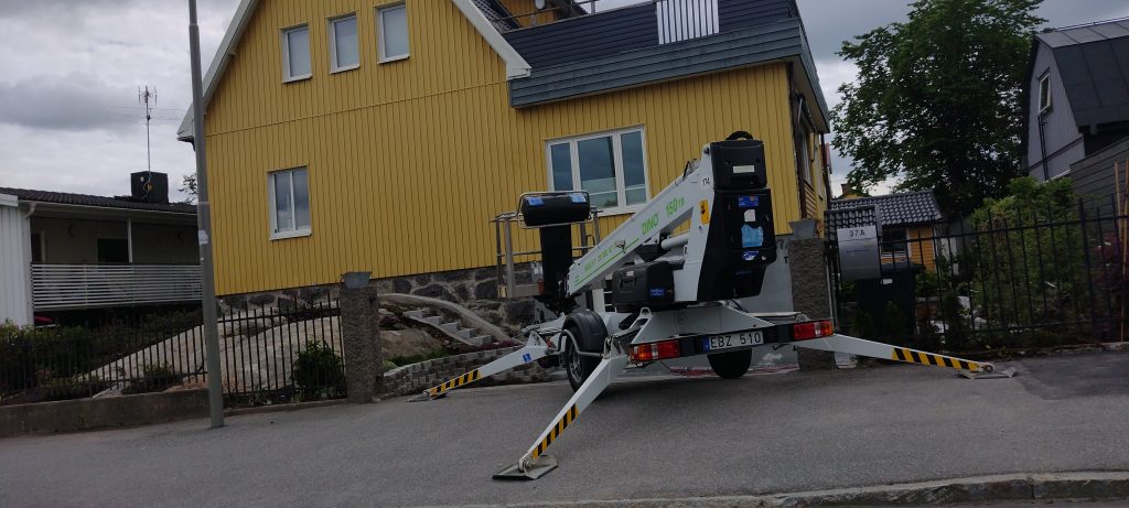 Kollane maja ja korvtõstuk tänaval fassaaditööde ajal