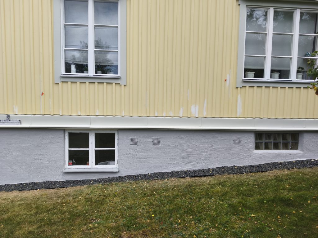 Kollane voodrilaud, aknad ja valmis sokkel maja seinal