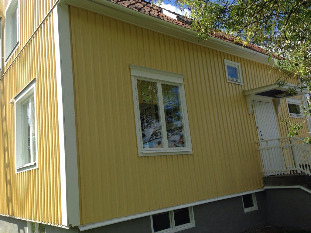 Kollaseks värvitud külgfassaad ja valged aknapiirded