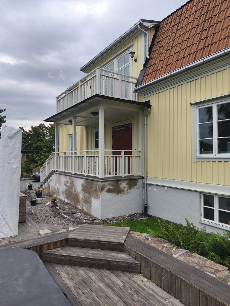 Kollane puitmaja ja kahjustatud sokkel terrassi kõrval