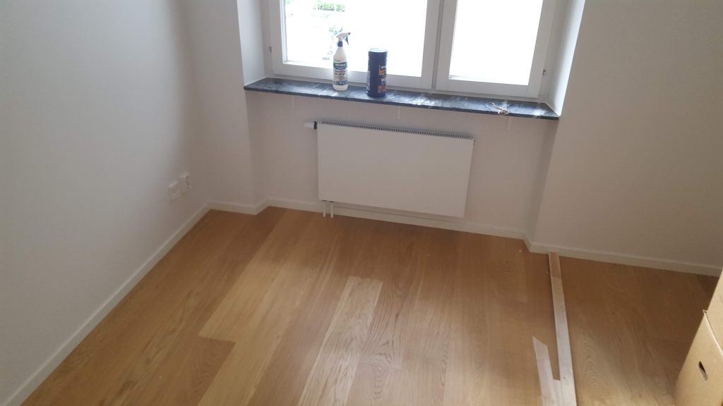 Värvitud sein ja radiaator akna all, puitparkett põrandal