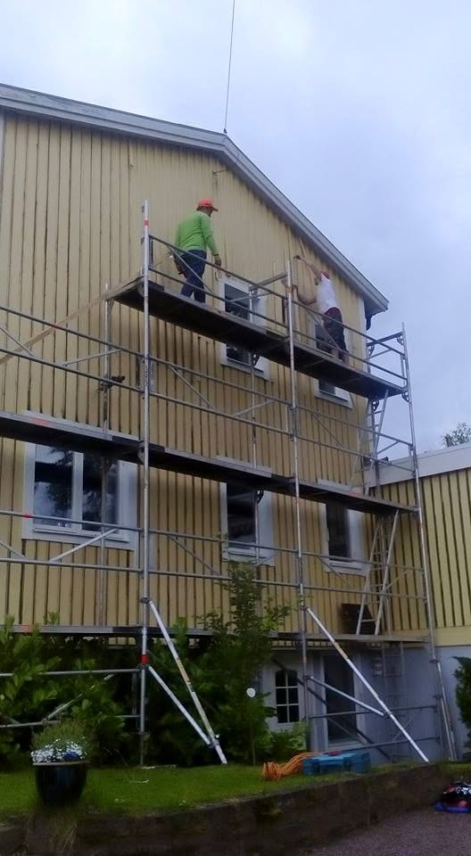 Töötajad tellingutel kollase kortermaja fassaadi värvimas