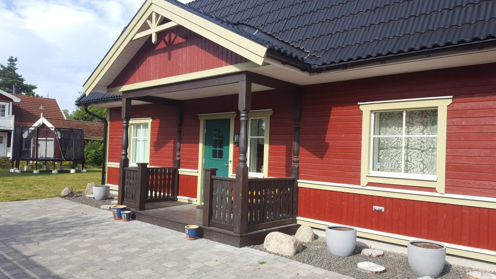 Punase uue maja veranda, valged piirded ja voodrilaud