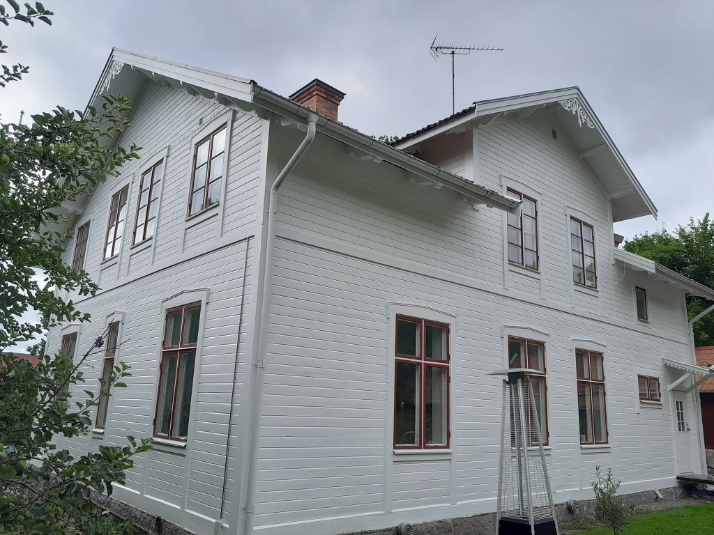 Valgeks värvitud villa külgfassaad ja kivisokkel pärast tööd